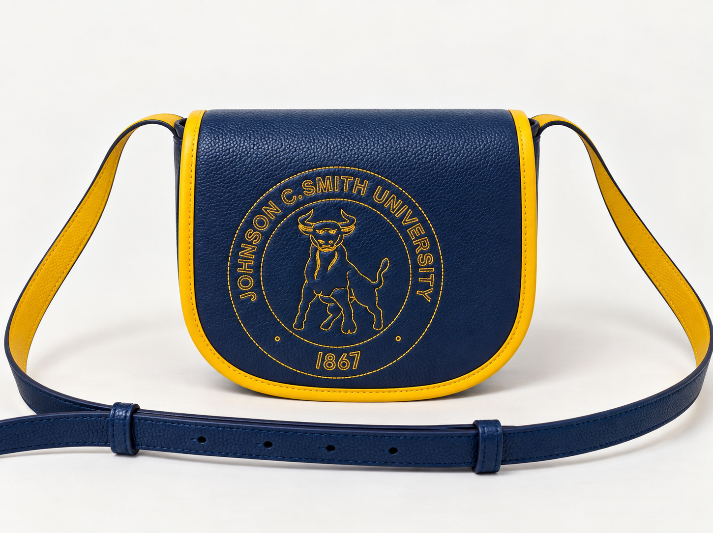 JCSU Classic Crossbody in navy leather with gold-trimmed flap and stitched Golden Bull seal, resting on warm cream backdrop